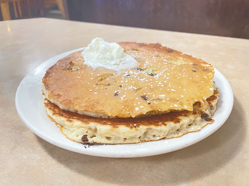 Two large pancakes topped with butter on a white plate. 