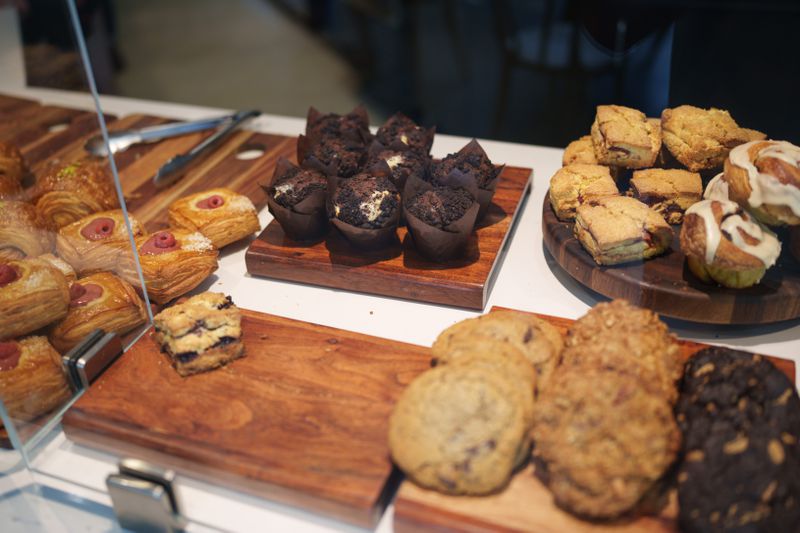An assortment of pastries on wooden blocks on a white counter behind glass. 