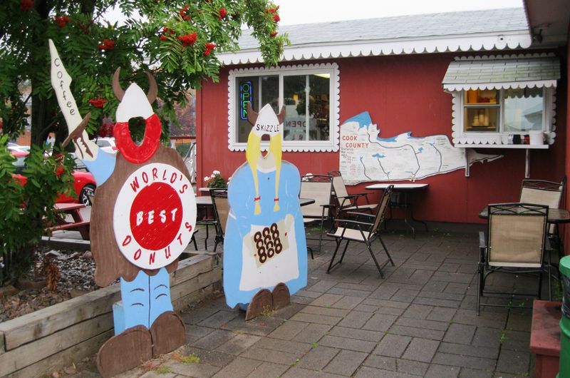 Face-in-hole viking cutouts on a small patio in front of a small red building with a service window and white trim.