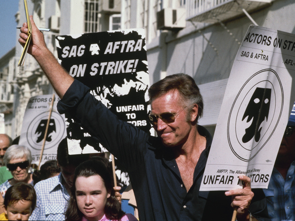 Actor Charlton Heston waves to fans while walking the picket line outside Paramount Studios in Hollywood during the Screen Actors Guild and American Federation of Television and Radio Artists strike in August 1980.