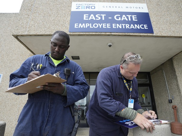Autoworkers Jalen Patterson, left, and David McHenry fill out a pledge in support of the UAW outside the General Motors Factory Zero plant in Hamtramck, Mich., on July 12.