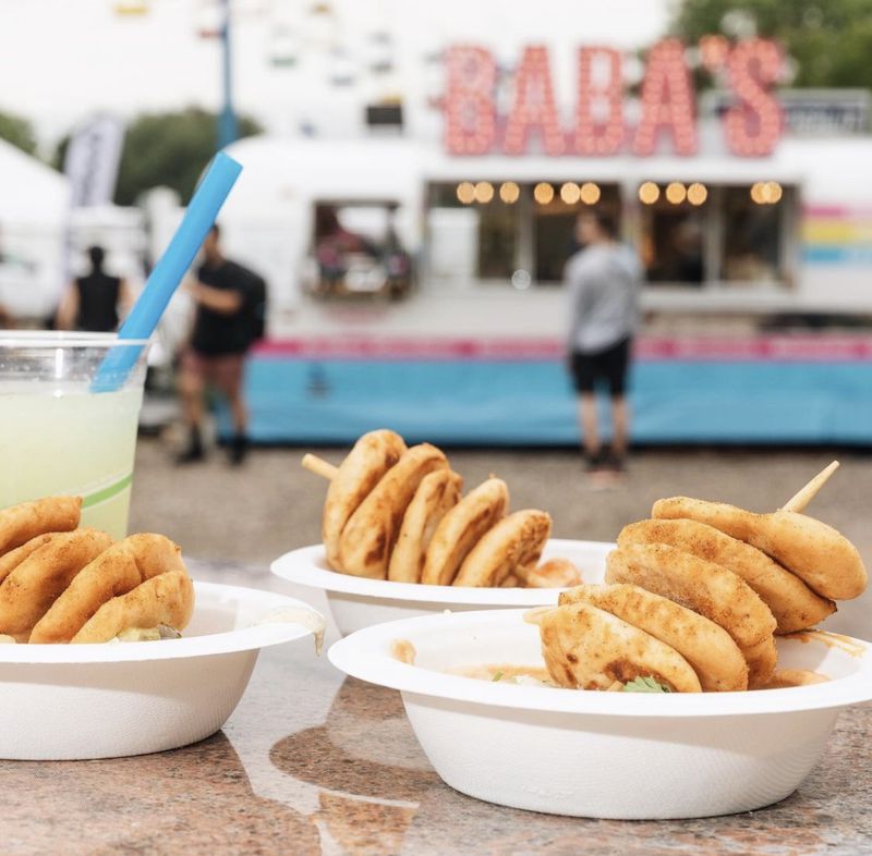 Three hummus bowls topped with small pitas on a skewer in front of a truck that says “Baba’s.”