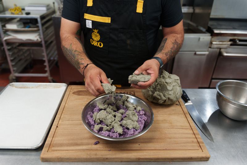Gustavo Romero tears off hunks of the blue corn masa and adds it to the bowl of mashed purple potatoes. 