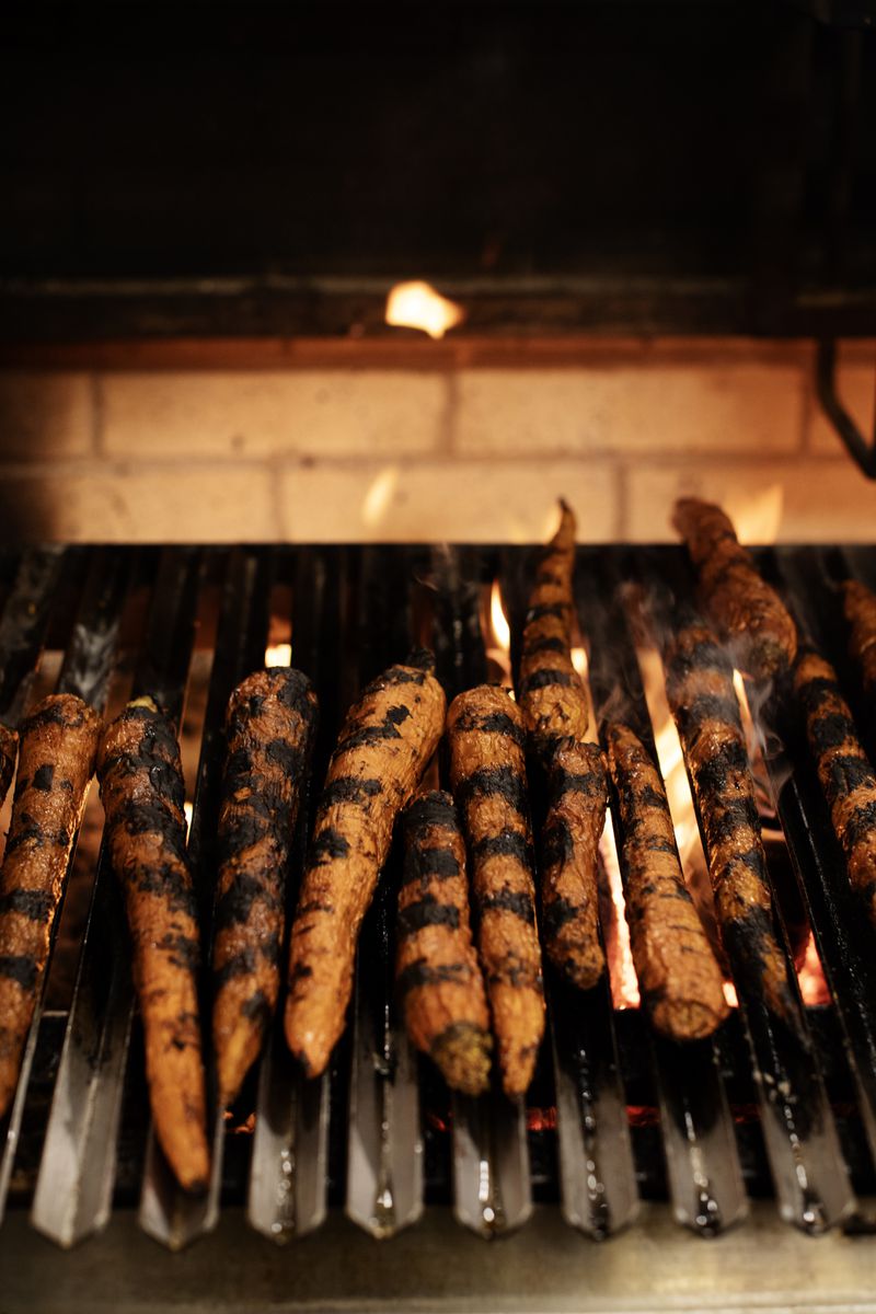 Skewers of chorizo above a fired grill. 