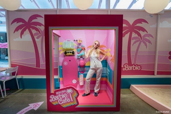 a woman poses inside a Barbie box