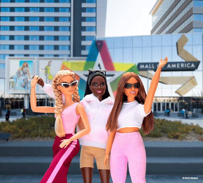 three barbie dolls pose in front of the MOA