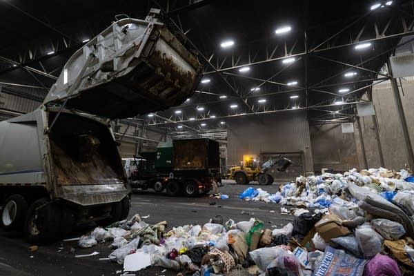 Trucks deliver their loads of garbage in a large room