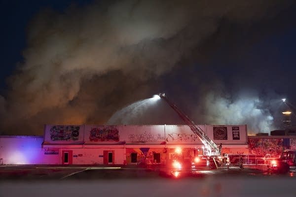 A fire crew sprays a burning building