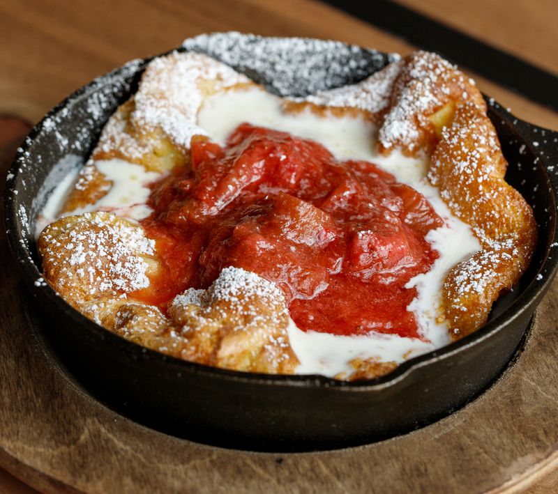 A Dutch baby with strawberry compote in a black iron skillet. 