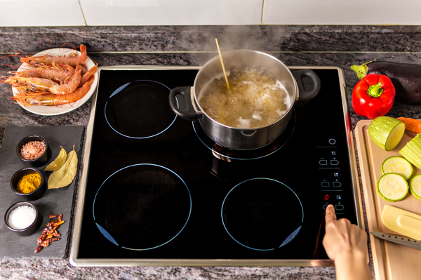 An induction stove uses magnetism to heat a pan and consumes less energy than a traditional electric stove.