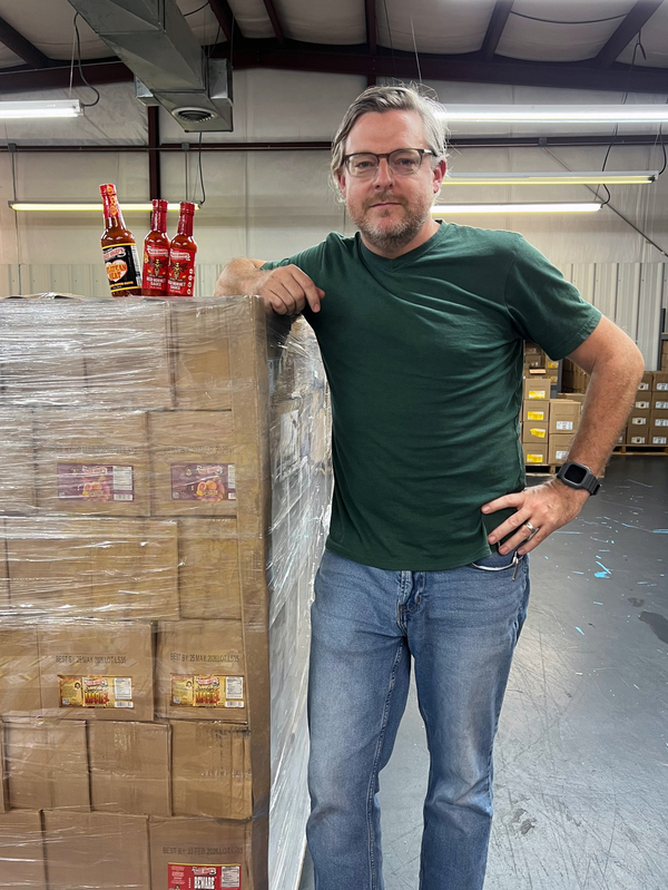 Nicholas Parks, president of SnobFoods.com, poses in a warehouse where he stores hot sauces that he sells on Amazon.