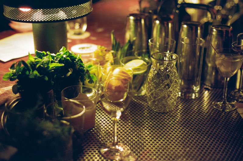 An assortment of glasses and cocktail garnishes on a drip tray of a cocktail bar.