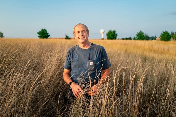A man stands in a field of tall grass