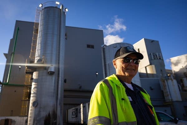 A man stands next to a processing plant