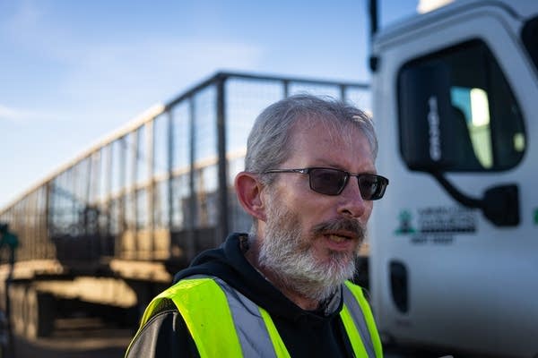 A man speaks as he stands next to a hauling truck