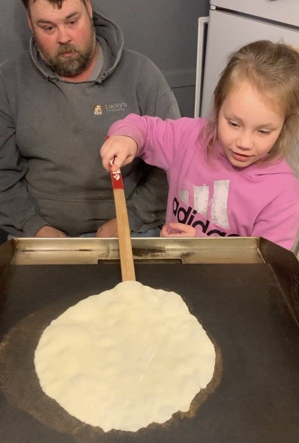 A person learning how to flip lefse