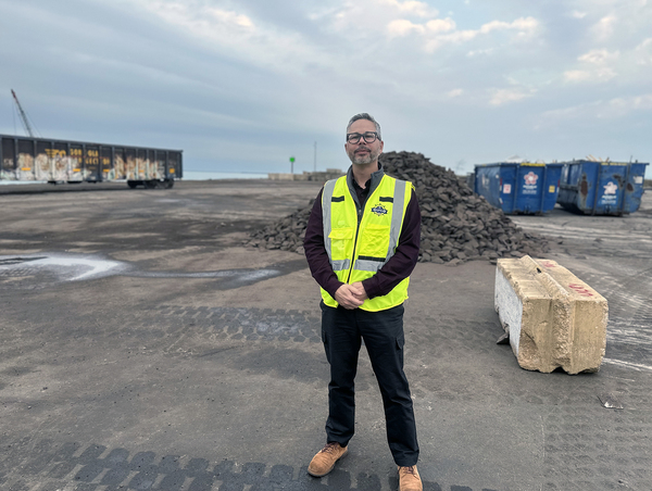 Erik Varela, executive director of the Illinois International Port District, stands beside a pile of iron ore at Iroquois Landing, where the Calumet River meets Lake Michigan, on Chicago's far south side