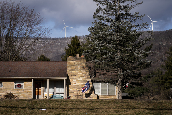 Wind turbines turn in the background as a flag that reads "Trump 2024" flies in the cold wind in Keyser on February 14.