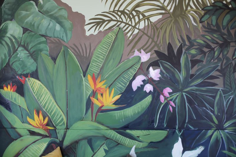 A hand-painted mural of vibrant green tropical plants and flowers. 