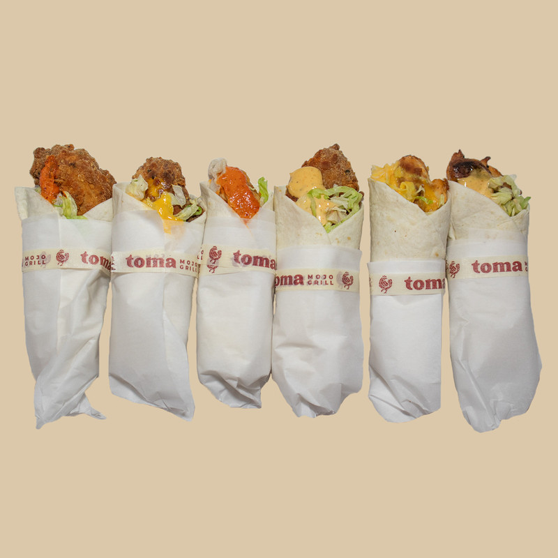 Six chicken snack wraps wrapped in white paper with a label that says “Toma Mojo” on a tan background.