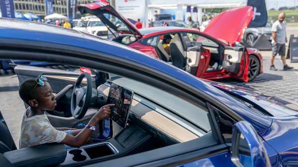 A young attendee examines a Tesla car during the Electrify Expo in Washington D.C. on July 23, 2023. The expo highlighted new and soon-to-be-released electric cars, bikes and other technology. Companies are racing to bring more vehicles to market, in a wider range of segments and at lower prices, to win over skeptical car shoppers. Tesla is working on a lower-cost next-generation platform.