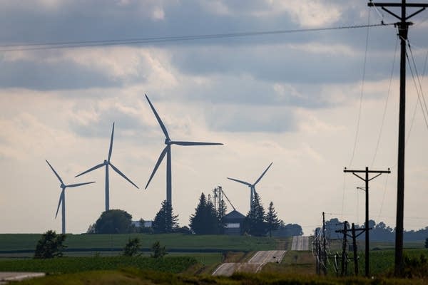 Transmission lines frame four wind turbines in the distance