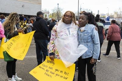 People hold signs and embrace