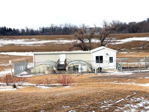 a small white building surrounded by a fence