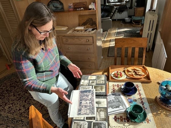 A woman looks over photographs on a coffee table.