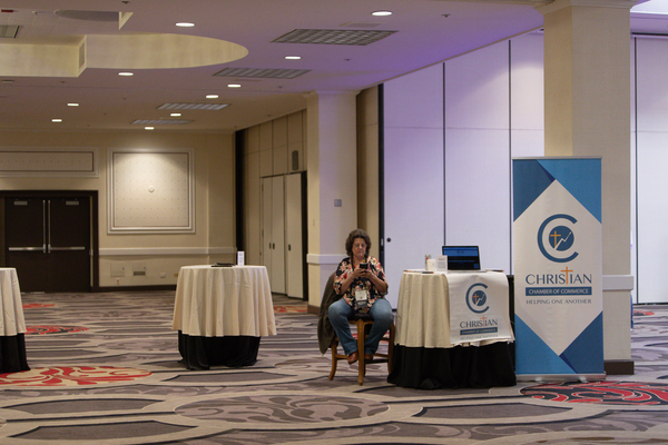 A woman sits at the Christian Chamber of Commerce booth at the RePlatform conference.