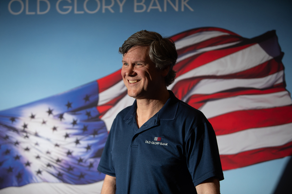 Eric Ohlhausen, chief strategy officer at Old Glory Bank, stands in front of his company's sign at the RePlatform conference.